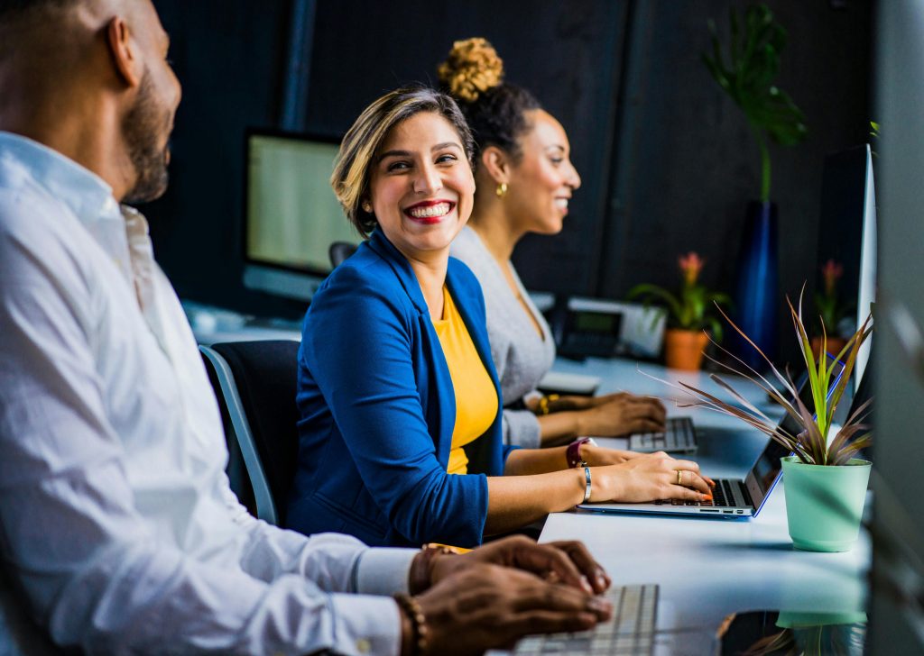 women smiling as she speaks to colleague in office.
